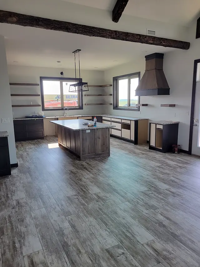 Open kitchen with an exposed beam and weathered gray plank flooring