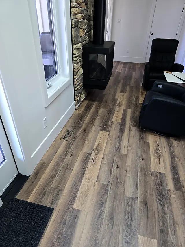Living room with a corner fireplace and brown plank flooring