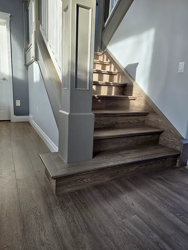 Gray wood staircase with a painted newel post