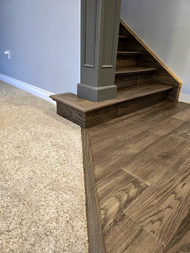 Carpet meeting wood flooring at the base of a staircase