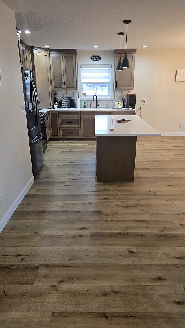 Kitchen with an island and warm oak-look plank flooring